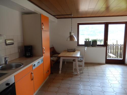シュタインドルフ・アム・オシアッハー・ゼーにあるHaus am Waldのキッチン(オレンジ色のキャビネット、テーブル、窓付)