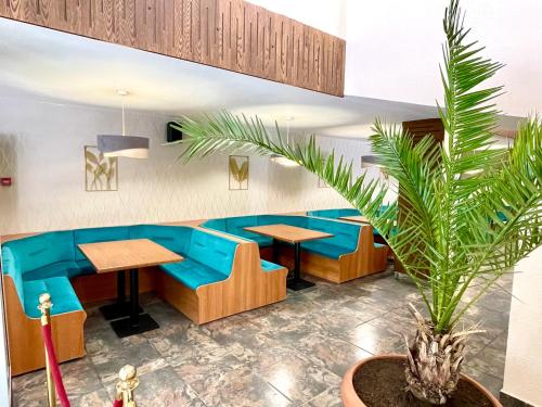 a restaurant with blue couches and tables and a plant at BSA Gradina Hotel & Aquapark - All Inclusive in Golden Sands