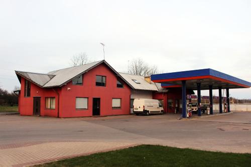 een rood gebouw met een busje geparkeerd bij een tankstation bij Motelis Astarte in Koknese