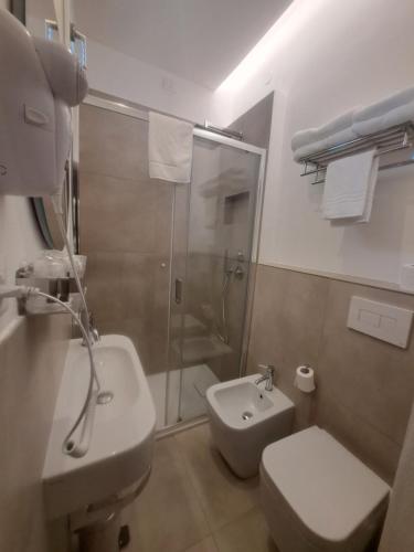 a bathroom with a shower and a toilet and a sink at Hotel Trieste in Senigallia