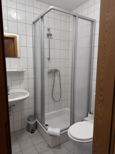 a bathroom with a shower and a toilet and a sink at Hotel Holtriemer Hof in Nenndorf