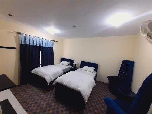 a hotel room with two beds and a chair at Ibex lodge Skardu in Skardu