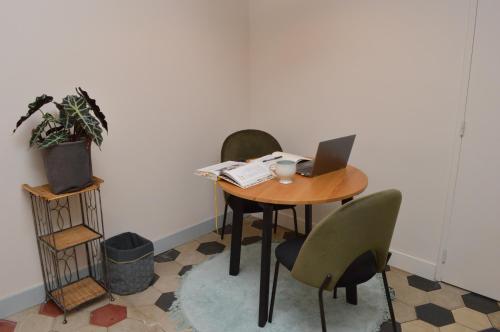 una mesa con un ordenador portátil y sillas en una habitación en Studio de charme au cœur de Lyon, en Lyon