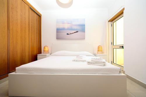 a bedroom with a white bed and a painting on the wall at B90 - Casa Sardinha in Lagos in Lagos