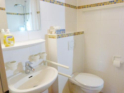 a white bathroom with a toilet and a sink at Dat Spatzenhus 1 in Wangerooge