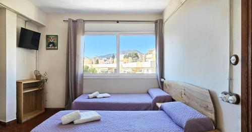 Habitación pequeña con 2 camas y ventana en Hostal La Palmera, en Torremolinos