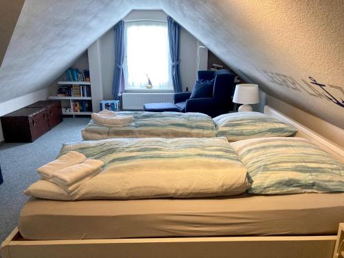 a bedroom with two beds and a chair and a window at Res a Ros 26 in Wangerooge