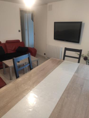 uma sala de estar com uma mesa e uma televisão em La Cigogne em Éclaron