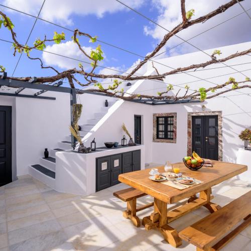 a patio with a wooden table and a kitchen at Firalia, Casa in Rock Suites in Fira