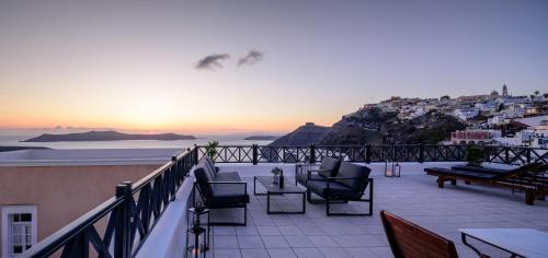a balcony with chairs and a view of a city at Firalia, Casa in Rock Suites in Fira
