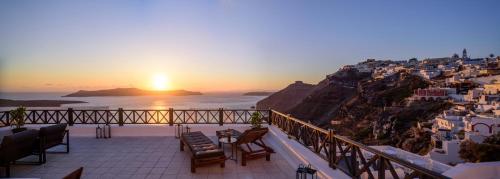 a balcony with a view of the ocean and a sunset at Firalia, Casa in Rock Suites in Fira