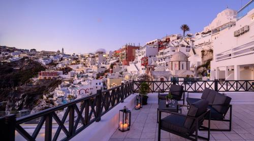 a balcony with chairs and a view of a city at Firalia, Casa in Rock Suites in Fira