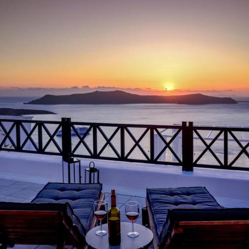 a view of a sunset from a balcony with wine glasses at Firalia, Casa in Rock Suites in Fira