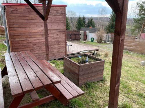 a wooden bench sitting in a yard with a planter at Fox House Tisá / Rájec in Tisá