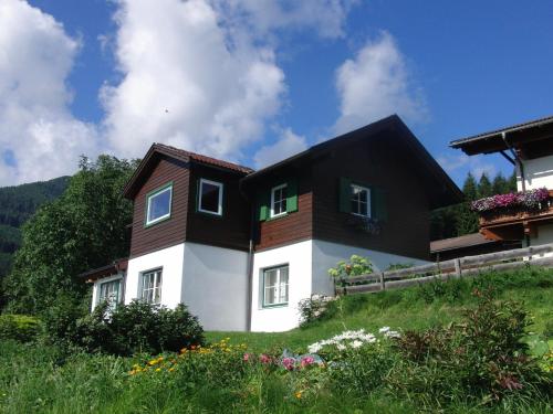 ein schwarzes und weißes Haus auf einem Hügel mit Blumen in der Unterkunft Nockhof in Innsbruck