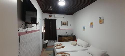 a small room with a bed and a flat screen tv at Hostel Néli in Aparecida