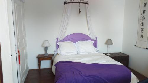 - un lit avec une tête de lit violette et des oreillers blancs dans l'établissement La maison de Léa, à Dinard