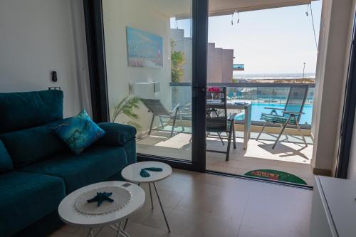 a living room with a couch and a view of a balcony at Calypso in Cotillo