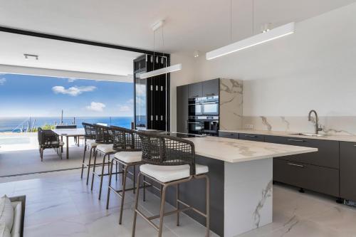 a kitchen with a bar with chairs and a view of the ocean at Villa Regatta in Hato