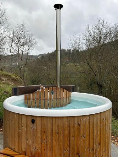 a hot tub with a fountain in a wooden enclosure at Moulin de Joumard, gîtes, chambres et table d'hôtes de charme , jacuzzi, sauna, piscine et bain nordique Etablissement 4 étoiles in Aubazat