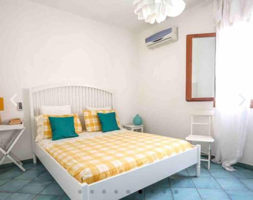 Dormitorio blanco con cama con almohadas amarillas y azules en Villa Ginkò 10 posti Letto Torre Lapillo Resort 900 Mt dal Mare, en Torre Lapillo