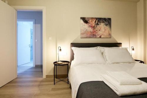 a bedroom with a large white bed with a painting above it at Aellō luxury apartments in Markopoulo