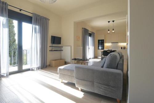 a living room with a gray couch and a living room with a kitchen at Aellō luxury apartments in Markopoulo