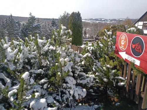 a snow covered bush with a sign next to a fence at Fox House Tisá / Rájec in Tisá