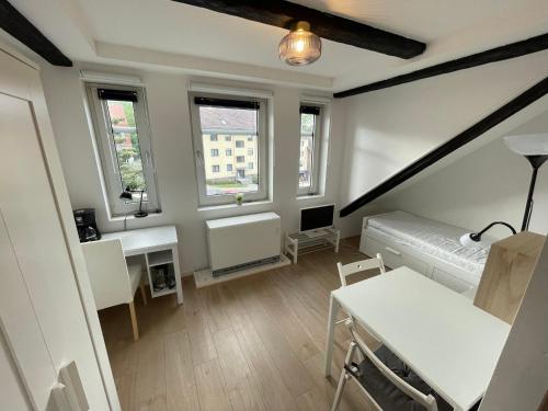a room with a bed and a desk and windows at Liebevoll eingerichtetes Ferienzimmer mit großen Garten in Clausthal-Zellerfeld