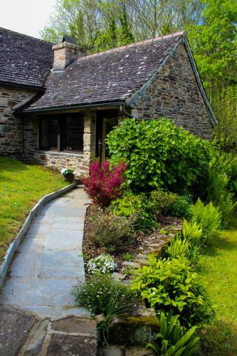 une maison en pierre avec une passerelle en face d'une cour dans l'établissement TY La Source, à Plestin-les-Grèves