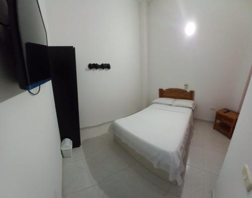 a small bedroom with a bed and a television at Hotel San Adolfo Carepa in Carepa