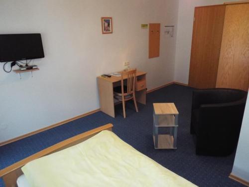 a room with a bed and a desk and a tv at Hotel garni Zum Reinhardswald in Gewissenruh