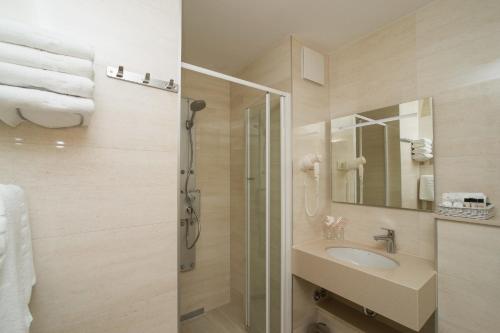 a bathroom with a shower and a sink and a mirror at Hotel Biokovo in Makarska