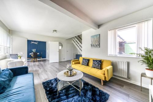 a living room with a yellow couch and a table at Contemporary 4 bedroom detached house with parking and city links in Croydon