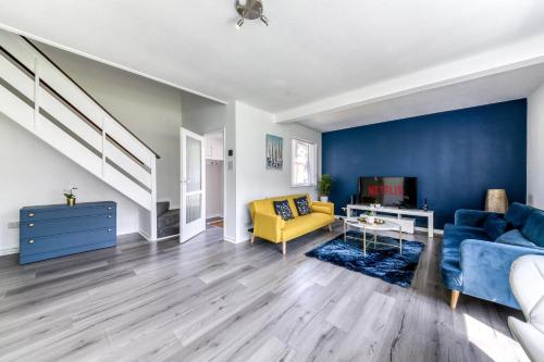 a living room with blue walls and a yellow couch at Contemporary 4 bedroom detached house with parking and city links in Croydon
