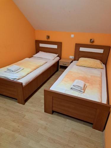 two beds in a room with orange walls at Guest House Pri Treh Lipah in Ptuj