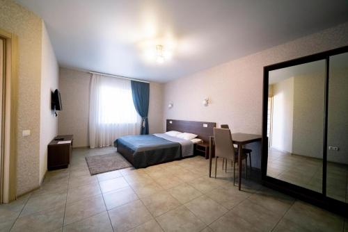 a hotel room with a bed and a table and a mirror at Райский Дворик in Pogreby