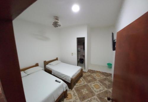 a room with two beds in a room with a door at Hotel San Adolfo Carepa in Carepa