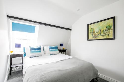 a white bedroom with a bed and a window at Chester Stays - Beautiful loft apartment with parking in Chester