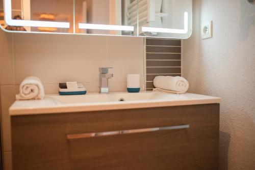 une salle de bain avec un lavabo et un miroir dans l'établissement Duplex familial proche plage et commerces, à Capbreton