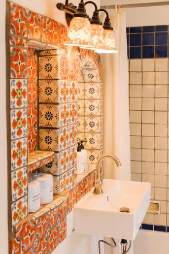 a bathroom with a sink and a tile wall at Pueblo Bonito Inn in Santa Fe