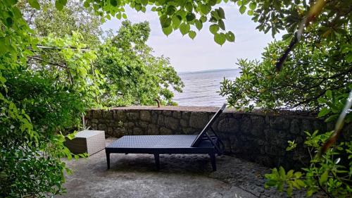 a bench sitting next to a stone wall next to the ocean at Aparatman Residence in Rijeka