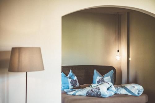 a room with a bed with pillows and a lamp at Bäcksteinerhof in Merano