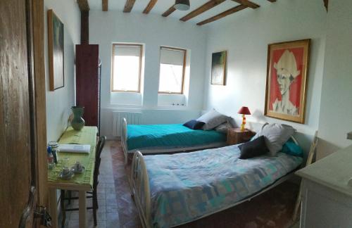 a bedroom with two beds and a table and two windows at Demeure de BoisClaireau in Le Mans