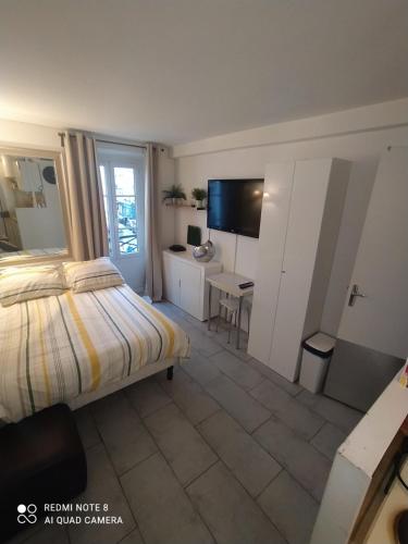 Dormitorio con cama, escritorio y TV en Studio à Montmartre, en París
