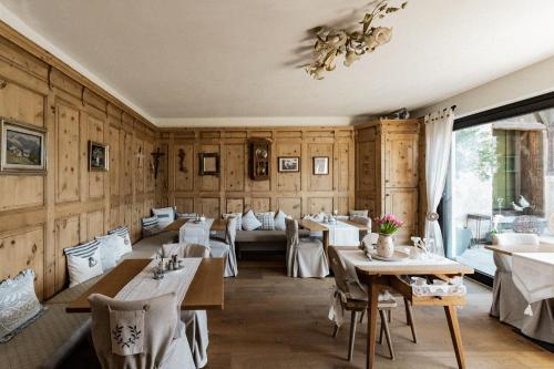ein Restaurant mit Holzwänden und Tischen sowie einem Kronleuchter in der Unterkunft Bäcksteinerhof in Meran