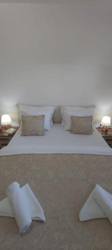 a large bed with white sheets and pillows on it at Villa Bella in Ilidža
