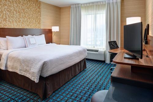 ein Hotelzimmer mit einem Bett und einem Schreibtisch mit einem TV in der Unterkunft Fairfield Inn & Suites by Marriott Detroit Troy in Troy