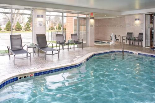 uma piscina num hotel com cadeiras e mesas em Fairfield Inn & Suites by Marriott Detroit Troy em Troy