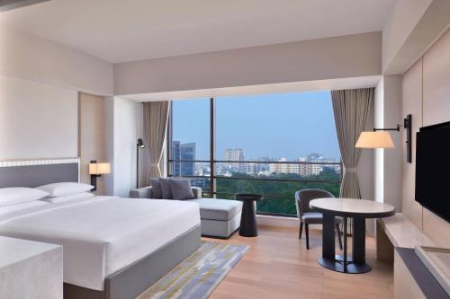 アーメダバードにあるCourtyard by Marriott Ahmedabad Sindhu Bhavan Roadのベッドと大きな窓が備わるホテルルームです。